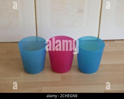 three colourful plastic beakers on a wooden kitchen worktop Stock Photo