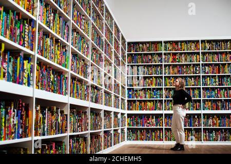 A staff member looks at Yinka Shonibare's work, The British Library, at Tate Modern, London, the latest artwork to be acquired by Tate. Stock Photo