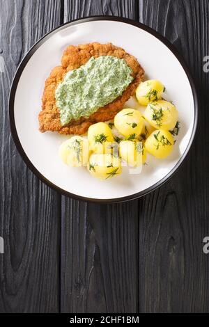 Traditional Frankfurt cuisine schnitzel with boiled new potatoes and green sauce close-up in a plate on the table. Vertical top view from above Stock Photo