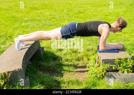 Young man performing plank exercise in an outdoors environment. Strengthen core muscles, exercise, keep fit, health Stock Photo