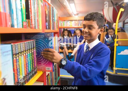 Adyan Hussain, 10, chooses a book to read with classmates onboard their new library bus, which was transformed by colleagues from Epsom Sainsbury's as part of the retailer's 150 Days of Community Initiative, at Riverview Primary School in Tolworth, Surrey. PA Photo. Issue date: Tuesday October 29, 2019. The former London bus has been repurposed and renovated as part of Sainsbury's anniversary scheme, which has seen 178,000 colleagues across the UK have the opportunity to volunteer for a cause of their choice in their local community. Photo credit should read: David Parry/PA Wire Stock Photo