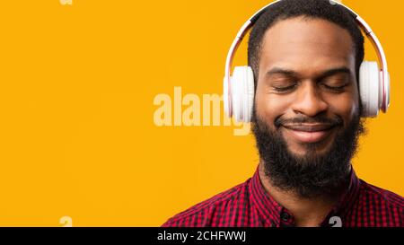 Smiling black man enjoying music using headphones Stock Photo