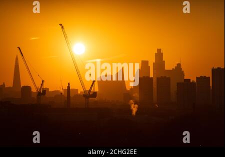 The sun sets behind tower cranes and the London skyline, including the Shard (left) and skyscrapers in the city financial district of London. PA Photo. Picture date: Tuesday January 21, 2020. Photo credit should read: Dominic Lipinski/PA Wire Stock Photo