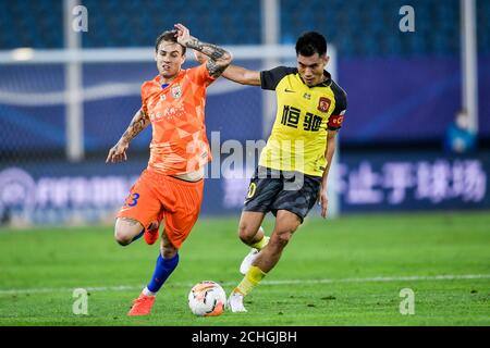 Brazilian football player Roger Krug Guedes, known as Roger Guedes, of Shandong Luneng Taishan F.C., left, struggles for the ball during the eleventh-round match of 2020 Chinese Super League (CSL) against Guangzhou Evergrande Taobao F.C., Dalian city, northeast China's Liaoning province, 13 September 2020. Shandong Luneng Taishan F.C. was defeated by Guangzhou Evergrande Taobao F.C. with 1-2. Stock Photo