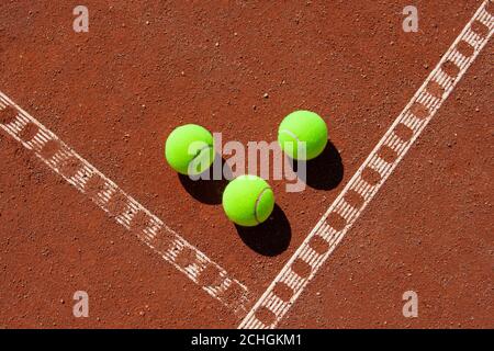 Three tennis balls in the corner of a clay field Stock Photo