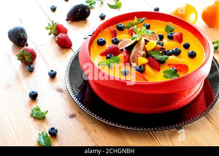 Delicious orange cheesecake decorated with fruits and mint leaves Stock Photo