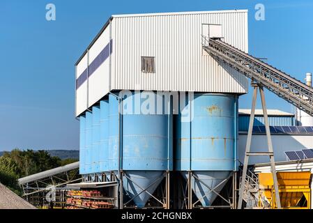 Big blue metallic Industrial silos for the production of cement at an industrial cement plant on the background of blue sky. Stock Photo