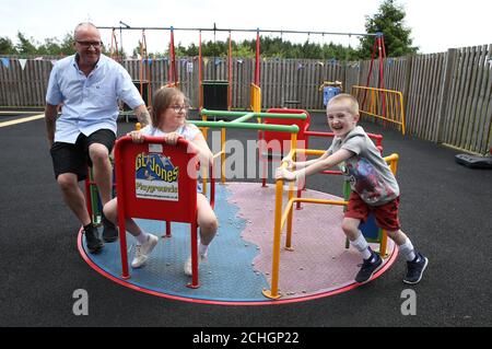 Embargoed to 0001 Monday June 22 Callum McMichael pushes his sister Laura and father Barry on the roundabout in the outside therapy area at the Craighalbert Centre. Coronavirus adaptations have been installed at the Scottish Centre for Children with Motor Impairments, Craighalbert Centre, Cumbernauld, as Scotland continues gradually lifting coronavirus lockdown measures. Stock Photo