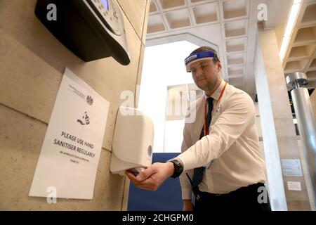 June 26th. A member of security uses a hand sanitiser in the main concourse at Glasgow Sheriff Court as social distance measures are shown following the announcement that Scotland will move to the second phase of its four-step plan to ease out of lockdown. Stock Photo