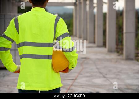 A worker in the uniform holding helmet for safety in the working construction site Stock Photo