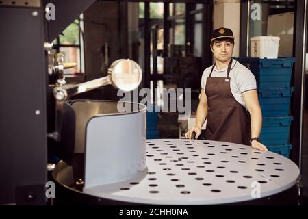 Handsome male worker using coffee roasting machine Stock Photo