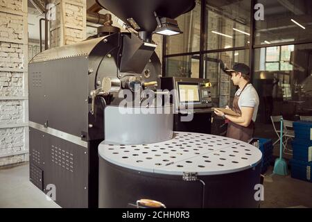 Male worker using control panel of coffee roasting machine Stock Photo