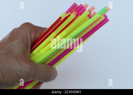 Plastic straws in a mans hand on the left side with space for text on the right side. Stock Photo