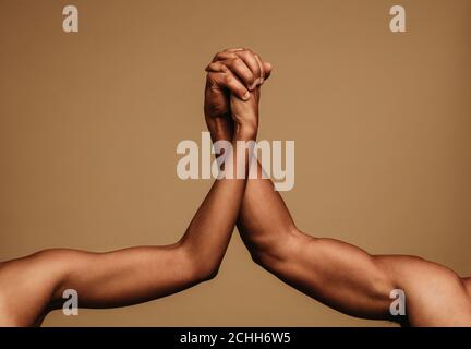 Cropped shot of two arms holding each other symbolising unity. Male and female hands holding each other. Stock Photo