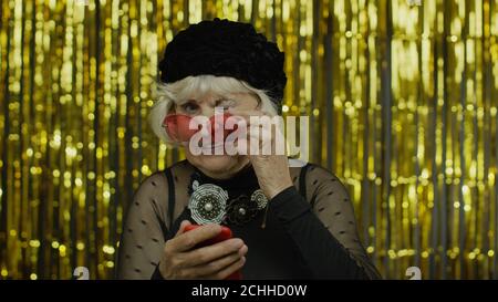 Stylish happy senior old woman typing message on mobile phone. Communication on social network, using smartphone app, online shopping. Elderly grandma with cellphone. Slow motion Stock Photo