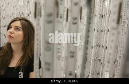 A visitor walks through the 'Fontes' installation by Brazilian artist Cildo Meireles, consisting of 6,000 carpenters rulers and 1,000 clocks, which is part of a new exhibition of the artists work at the Tate Modern, Southwark, London. Stock Photo