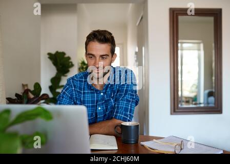 Young man working from home using a laptop Stock Photo