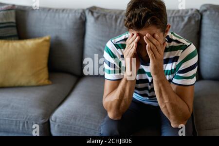 Depressed man sitting with his head in his hands Stock Photo