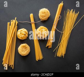 Pasta cooking concept. Raw pasta spaghetti and noodles variety on black background, top view Stock Photo