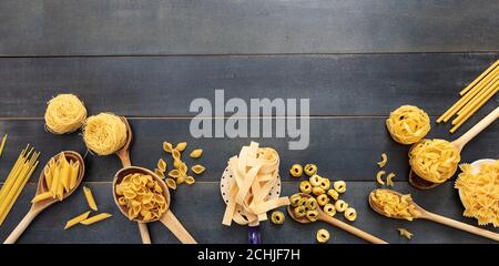 Pasta cooking concept. Raw pasta various shapes and spoons on blue wooden table background, top view Stock Photo