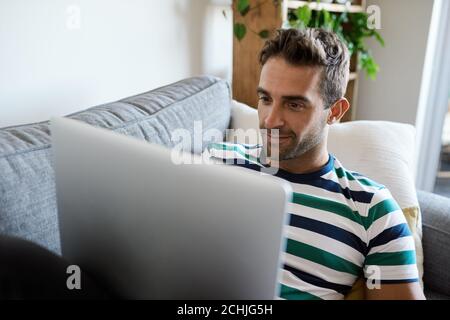 Young man relaxing on his sofa using a laptop Stock Photo