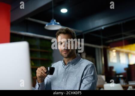 Young businessman drinking coffee while working at his desk Stock Photo