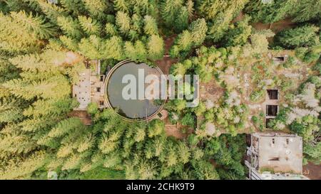 Top aerial view of abandoned water reservoir,tank, and buildings of old tin mine in Rolava,Ore mountains,Czech Republic. Beautiful nature from above.