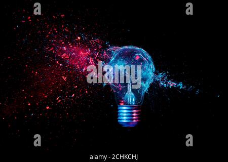 glass explosion of a filament light bulb on black. colored lights. Stock Photo