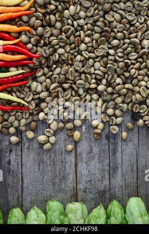 Hop twigs, green coffee beans, red chili  over wooden cracked table background. Vintage toned. Beer ingredients. Stock Photo