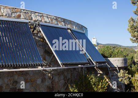 Solar water heating system installed on wall or roof of house. 3 panels of glass coaxial tubes with water to accumulate heat. Side view. Concept envir Stock Photo