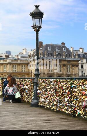 Lovers and padlocks in Paris. Two lovers lock their padlock on Pont des Arts. Stock Photo