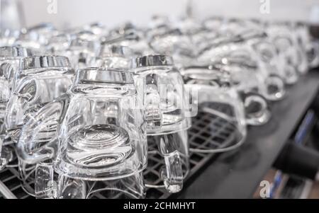Clear glass coffee cups stacked on the heating area of a commercial espresso coffee machine. Stock Photo