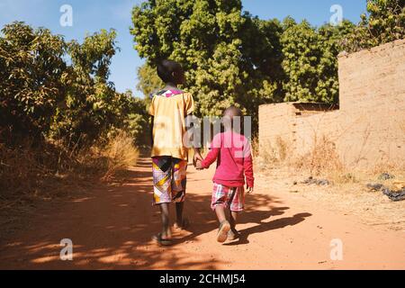 Two African Young Boys Walk Together in a Typical African Village Stock Photo