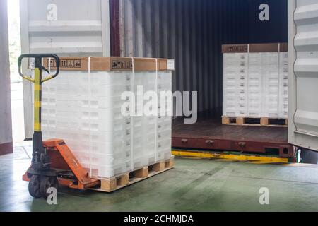Hand pallet truck loading shipping boxes and goods on wooden pallet at loading dock from container.(Soft focus) Stock Photo