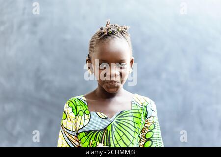 Cute African Beautiful Child Smiling Happy in front of Blackboard in Typical African Classroom Stock Photo