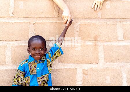 Smiling Cute Black Handsome Boy Standing Outdoors in Front of Wall Stock Photo