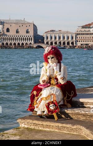 Venice, Veneto, Italy - Person in classical costume seated on steps of San Giorgio Maggiore at sunset, Venice Carnival, Veneto, Italy with view to the Stock Photo