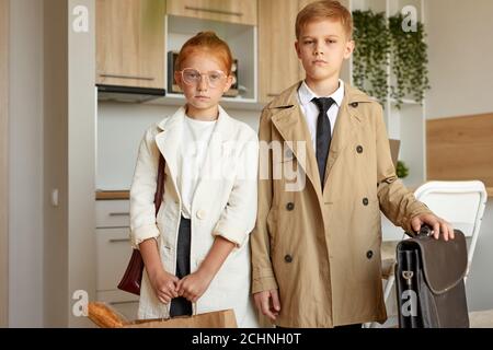 portrait of confident kids couple pretend to be adults, young business boy and girl in formal wear seriously look at camera, indoors Stock Photo