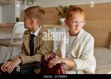 offended on each other girl and boy sit on bed in coats, they have no talk, keep silence, indoors Stock Photo