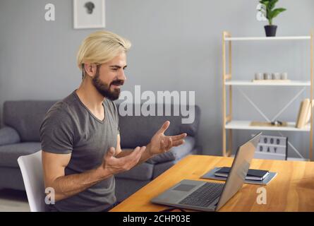 Man sitting at home, looking at laptop screen and smiling during online during meeting Stock Photo