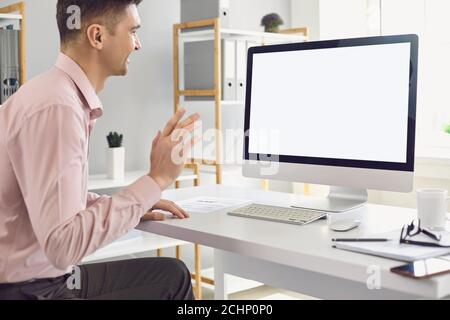 Man using personal desktop computer for teleconference and waving hand during video call Stock Photo