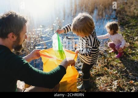 Father with small kids collecting rubbish outdoors in nature, plogging concept. Stock Photo