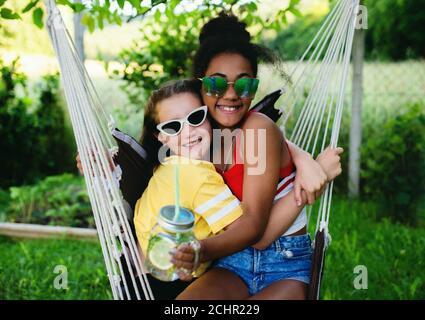 Front view of young teenager girls friends outdoors in garden, hugging. Stock Photo