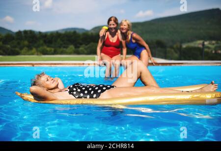 Senior women in swimming pool outdoors in backyard, relaxing. Stock Photo