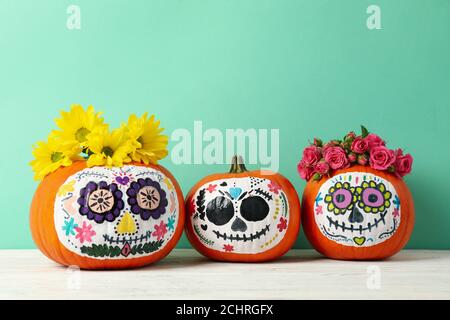 Pumpkins with catrina skull makeup and flowers on blue background