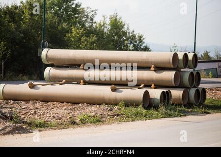 Large sewer pipes, slid along the road, ready for installation, reconstruction of roads and sewer networks Stock Photo