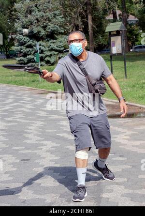 A man walks in the park while bouncing a ball of his tennis raquet. In Kissena Park, Flushing, New York City. Stock Photo