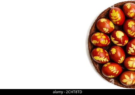 Easter eggs dyed with onion peels with a pattern of fresh leaves of plants in a wicker basket on a white background. DIY. Mockup of Easter card Stock Photo