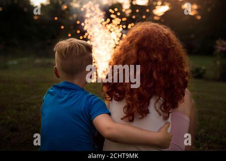 Two Siblings Sitting Together Watching Fireworks on the Fourth of July Stock Photo