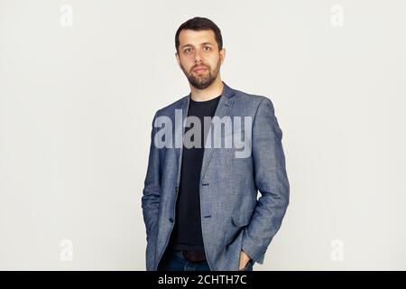 Portrait of a young male entrepreneur, looking at the camera with a sad face, a businessman, disappointed by losses in the business. The man looks at the camera, isolated through a gray wall with Stock Photo